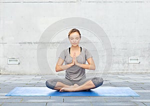Woman making yoga meditation in lotus pose on mat