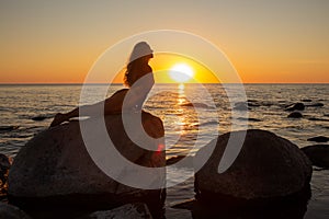 A woman making yoga outside. Silhouette of long-haired slim woman in sunset on a sea. Ustrasana - camel pose. Mukha