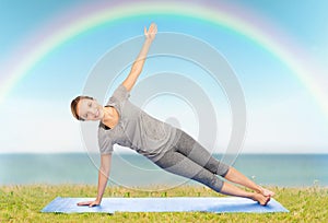 Woman making yoga in side plank pose on mat