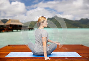 Woman making yoga in twist pose on mat outdoors