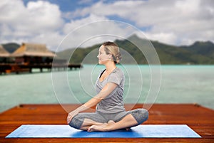 Woman making yoga in twist pose on mat outdoors