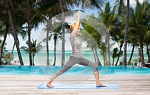 Woman making yoga warrior pose on mat