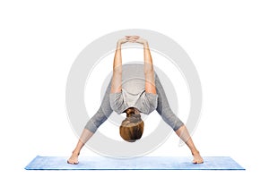 Woman making yoga wide-legged forward bend on mat