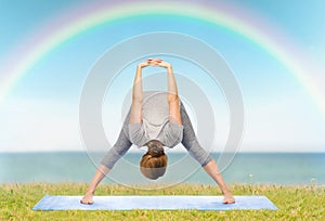 Woman making yoga wide-legged forward bend on mat