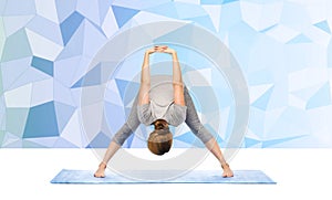 Woman making yoga wide-legged forward bend on mat