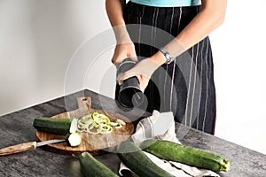 Woman making zucchini spaghetti on kitchen table