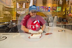 Woman makingp Pretzel dogs in a store window