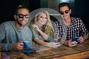 Woman with male friends wearing sunglasses in coffee shop