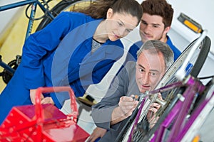 woman and man apprentices as bike mechanics in workshop reparing