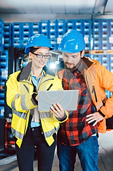 Woman and man as workers in logistics center using computer