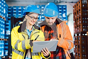 Woman and man as workers in logistics center using computer