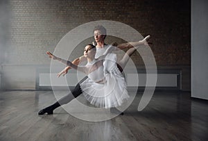 Woman and man ballet dancers in dynamic action against studio background