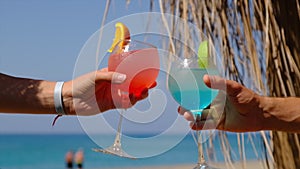 A woman and a man on the beach are drinking a cocktail. Selective focus.