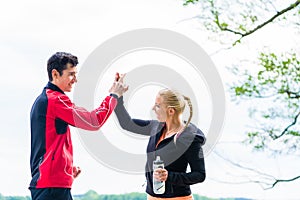 Woman and man at break from running giving each other a high fiv