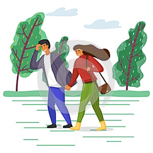 Woman and man in casual clothes walk in the park on the road along the tree alley in windy weather