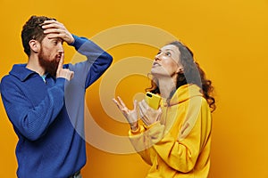 Woman man cheerful couple with phones in hand social networking and communication crooked smile fun and fight, in yellow