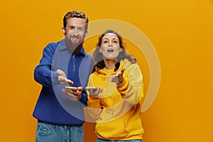 Woman man cheerful couple with phones in hand social networking and communication crooked smile fun and fight, in yellow