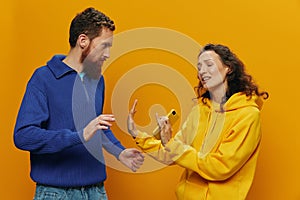 Woman man cheerful couple with phones in hand social networking and communication crooked smile fun and fight, in yellow