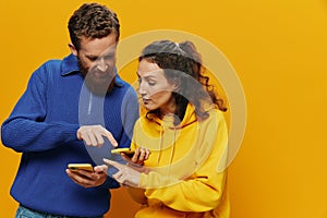 Woman man cheerful couple with phones in hand social networking and communication crooked smile fun and fight, in yellow