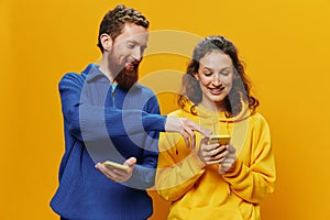 Woman man cheerful couple with phones in hand social networking and communication crooked smile fun and fight, in yellow