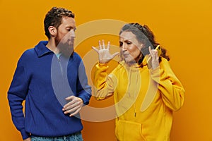 Woman man cheerful couple with phones in hand social networking and communication crooked smile fun and fight, in yellow