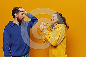 Woman man cheerful couple with phones in hand social networking and communication crooked smile fun and fight, in yellow