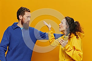 Woman man cheerful couple with phones in hand social networking and communication crooked smile fun and fight, in yellow
