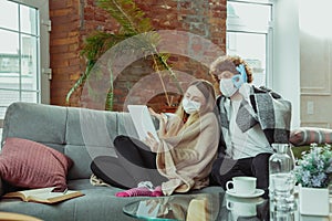 Woman and man, couple in protective masks and gloves  at home with coronavirus symptoms