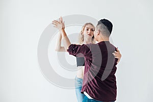 a woman and a man dancing to the music of a bachata in a white hall