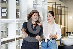 Woman and man discussing shopping list and pointing to something in store