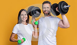 Woman man do sport training exercise isolated on yellow. Athlete couple with barbell and dumbbell. Family sport. Fitness