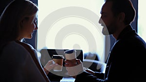 Woman and man drinking coffee from disposable cups. In love couple of middle aged business people sitting in a chair of