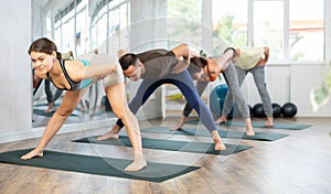 Woman and man at fitness classes practice yoga pose bending forward