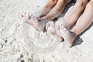 Woman and man foots in the sand at the beach chilling