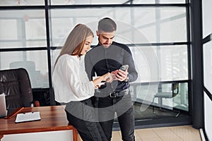 Woman and man in formal clothes with documents talking to each other in the office