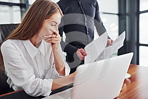 Woman and man in formal clothes working together indoors in the office by table with documents