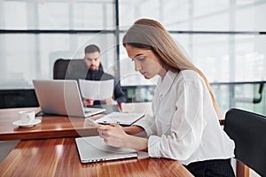 Woman and man in formal clothes working together indoors in the office by table with documents