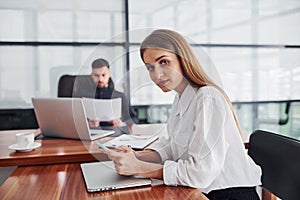 Woman and man in formal clothes working together indoors in the office by table with documents