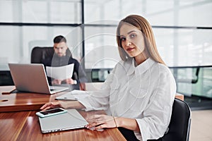 Woman and man in formal clothes working together indoors in the office by table with documents