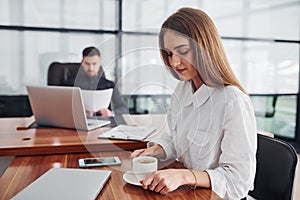 Woman and man in formal clothes working together indoors in the office by table with documents