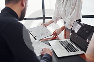 Woman and man in formal clothes working together indoors in the office by table with documents