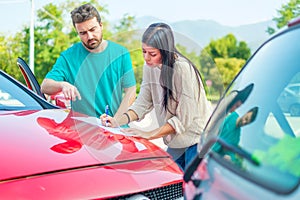 Woman and man friendly reporting the damage of the car after accident