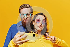 Woman and man funny couple with phones hand social networking and communication crooked do selfies smile fun, on yellow