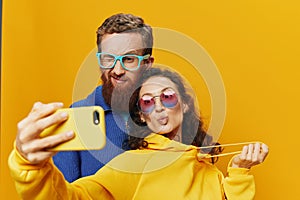 Woman and man funny couple with phones hand social networking and communication crooked do selfies smile fun, on yellow