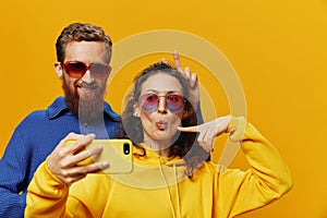 Woman and man funny couple with phones hand social networking and communication crooked do selfies smile fun, on yellow