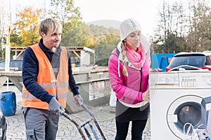 Woman and man giving electrical appliances to recycling center