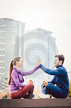 Woman and man giving hi-five after fitness sport in a city