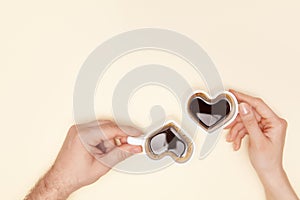 Woman and man hands hods heart shaped cup of coffee.