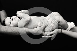 Woman and man hands holding a newborn. Mom, dad and baby. Close-up