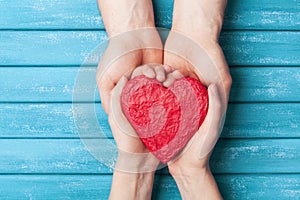 Woman and man hands holding red shape of heart. Saint valentine day background. Relationship, family and donorship concept.